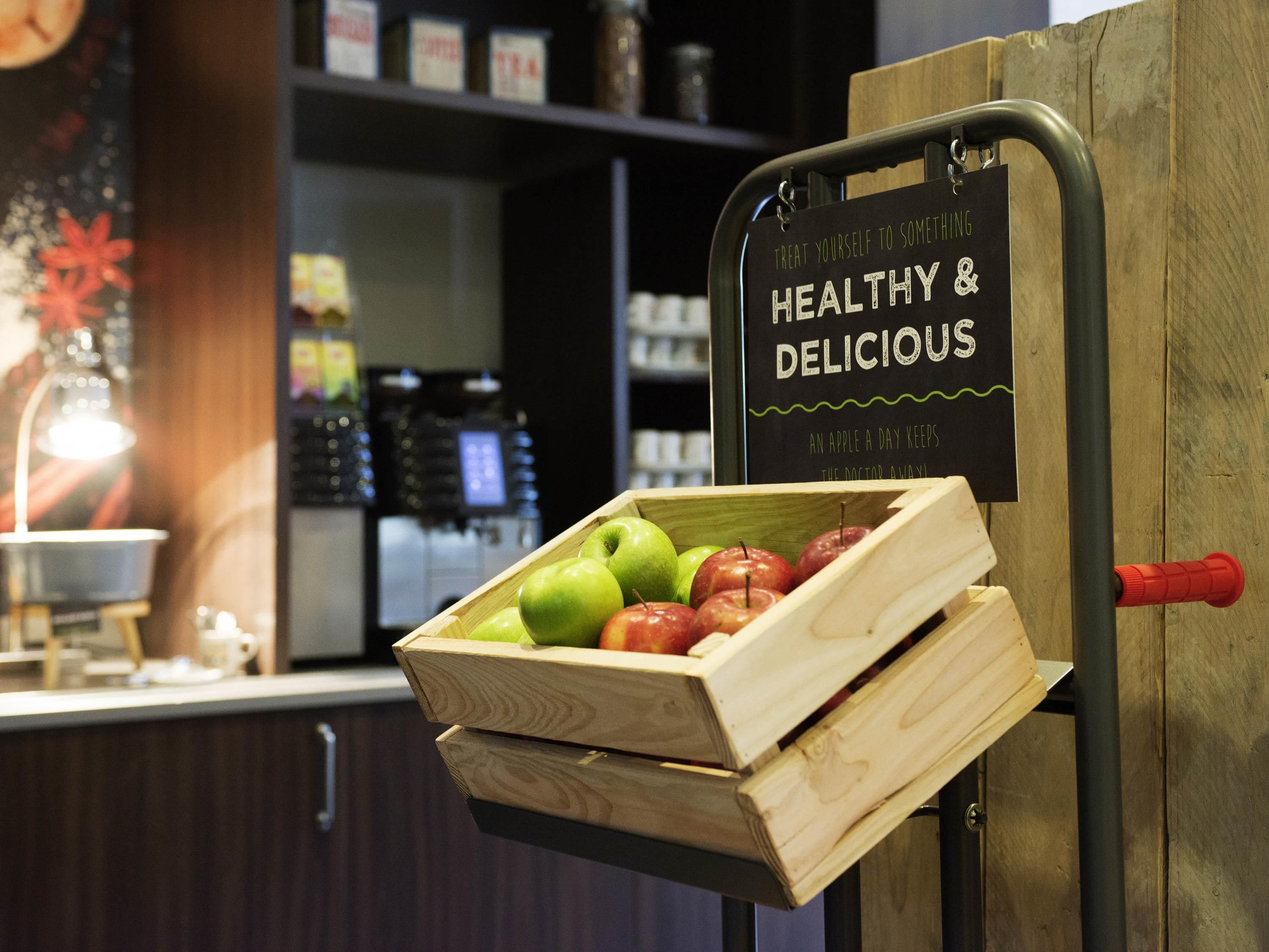 A wooden crate with apples and a sign that reads "TREAT YOURSELF TO SOMETHING HEALTHY & DELICIOUS".