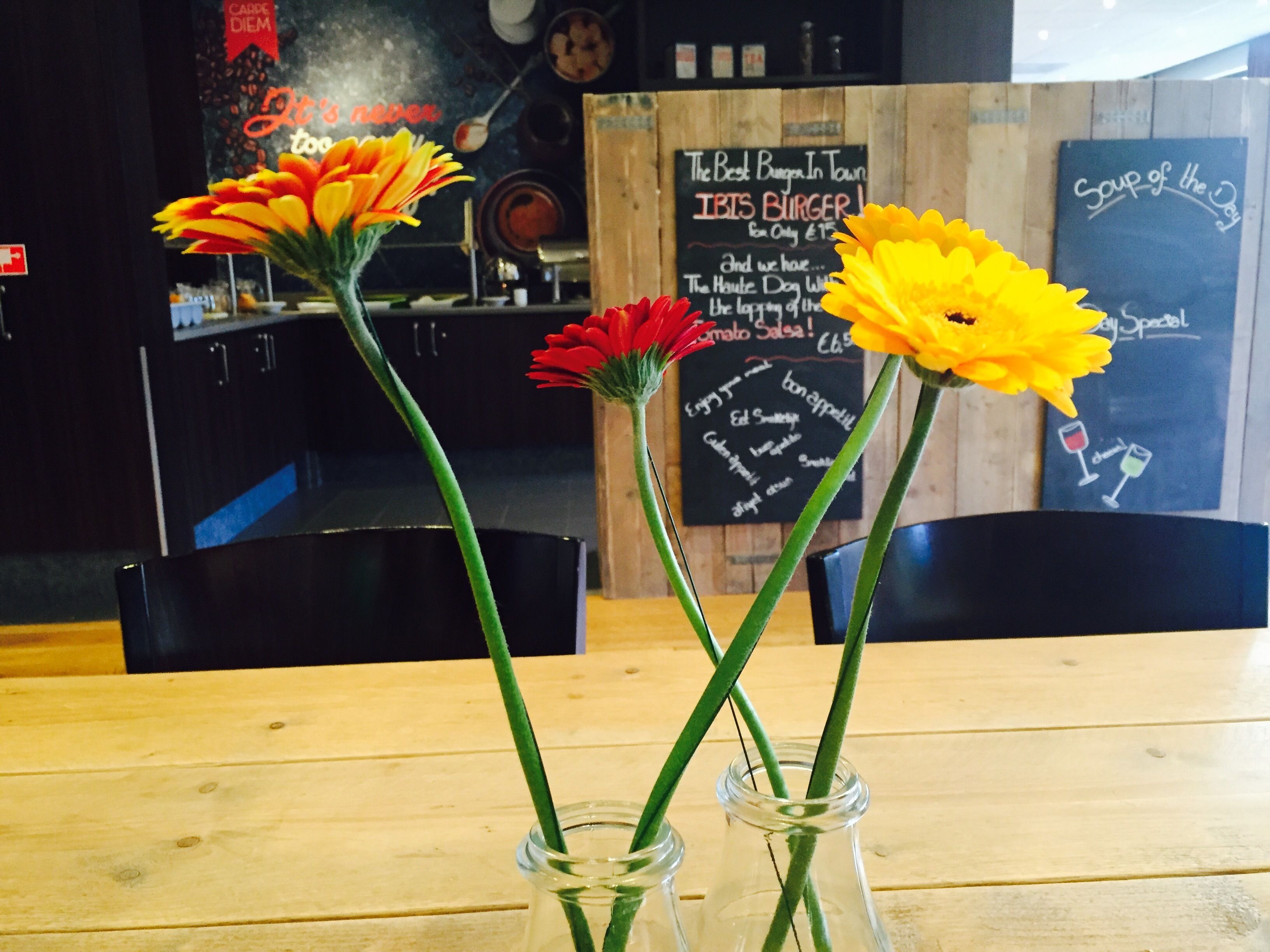 A wooden table with two glass vases containing flowers.