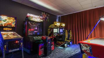 Een kamer met speelautomaten, een tafeltennistafel en een rood gordijn.