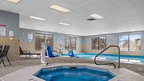 A pool area with a hot tub, lounge chairs, and a poolside seating area.
