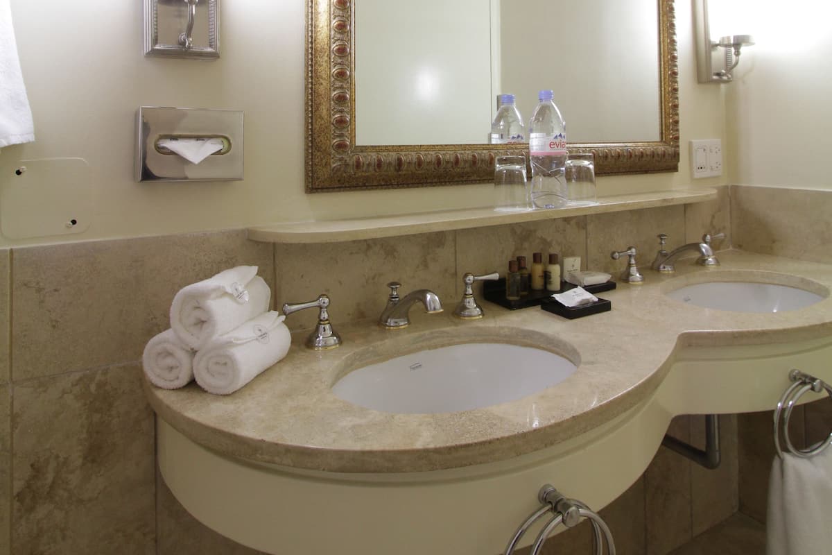Un baño con dos lavamanos, un espejo grande y un perchero para toallas.