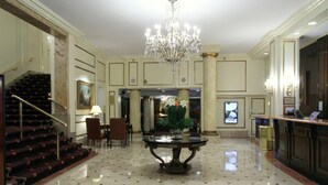 Un hall d’entrée agrémenté d’un lustre, un comptoir d’accueil, un escalier et un espace repas.