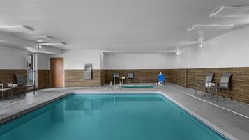 Una piscina interna con pavimento piastrellato, parete in legno e una porta.