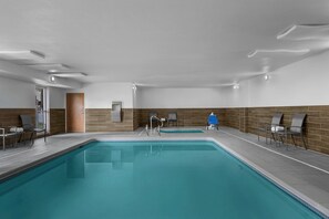 An indoor swimming pool with a tiled floor, a wooden wall, and a door. - Fairfield Inn By Marriott Boise (Boise)
