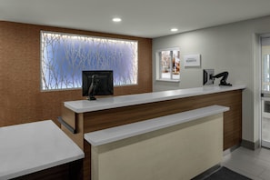 A reception desk with a computer monitor, a window with a view of bare trees, and a sign that reads "Marriott Bonvoy". - Fairfield Inn By Marriott Boise (Boise)
