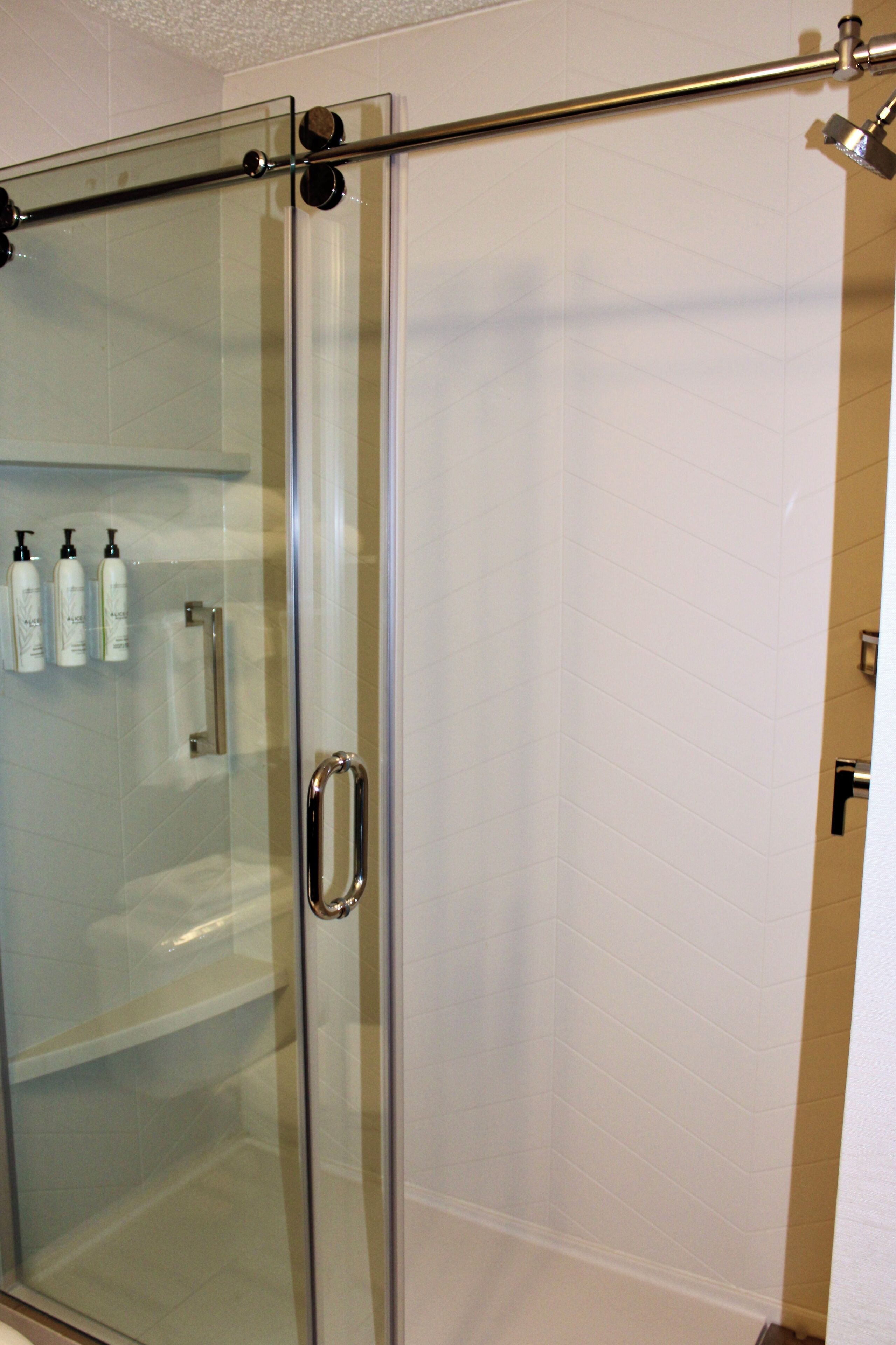 A glass-enclosed shower stall with a metal handle and a glass door.