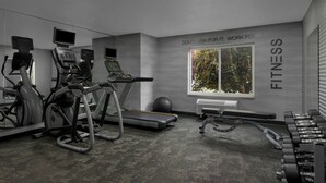 Un gimnasio moderno con máquinas de cardio, mancuernas y una frase motivadora en la pared.