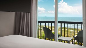 Una habitación de hotel con cama, televisión y balcón con sillas y una mesa.