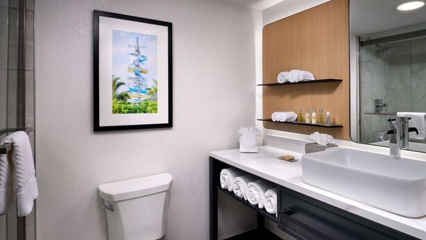Un baño moderno con inodoro, lavamanos y un cuadro en la pared.