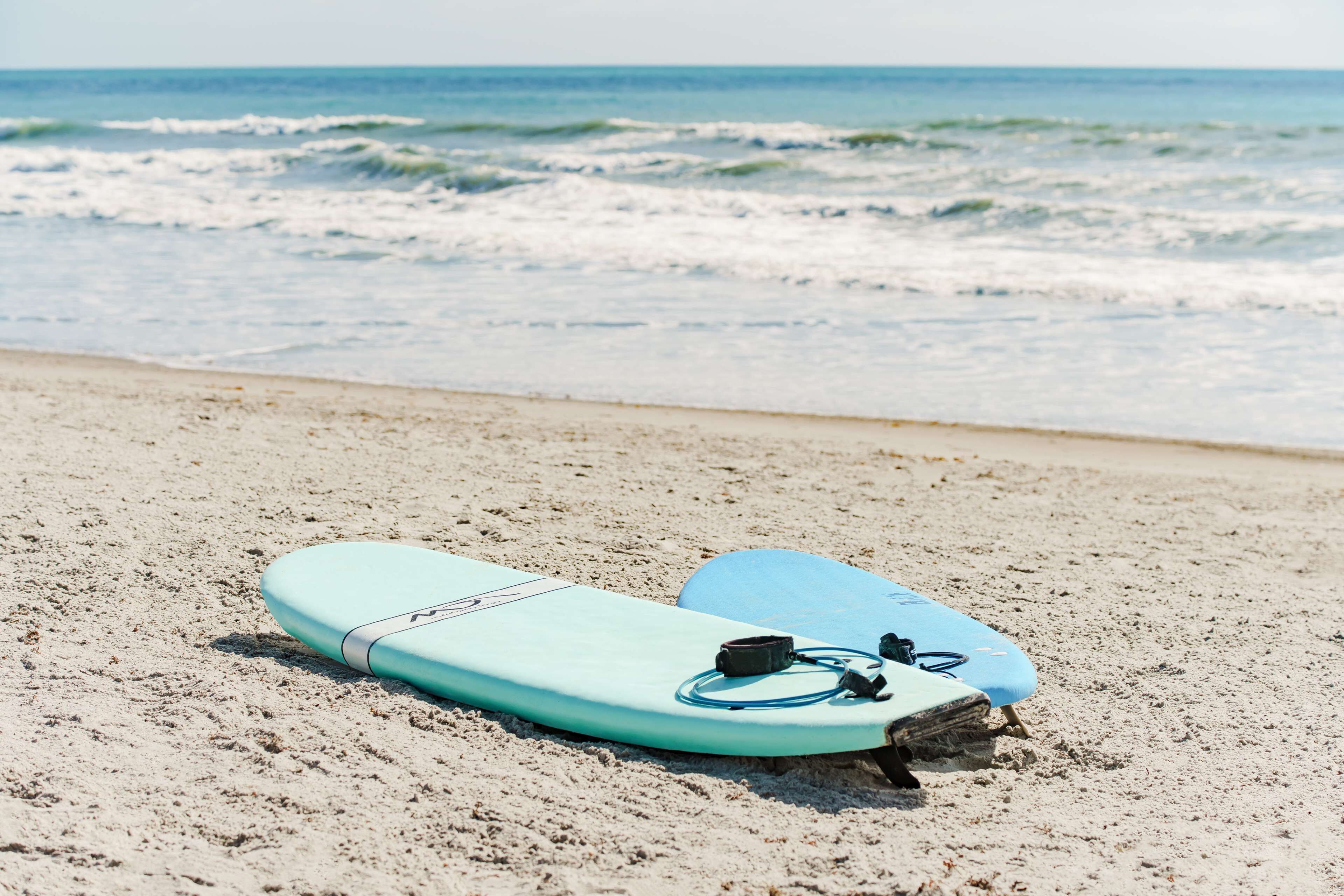 Two surfboards on a sandy beach with the ocean in the background.