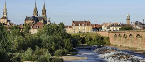A river with a bridge, buildings, and a church with spires.