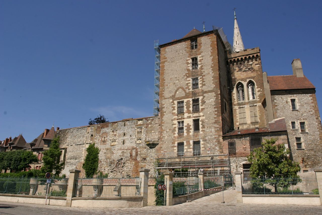 Un bâtiment historique en pierre, doté d’une tour imposante et de fenêtres en arc de cercle.
