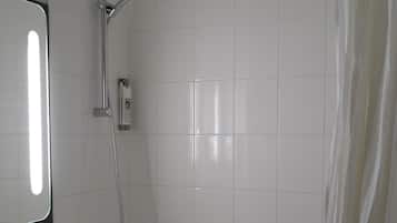 A bathroom with a white sink, mirror, and shower. There are towels hanging on the wall.