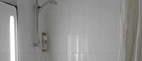 A bathroom with a white sink, mirror, and shower. There are towels hanging on the wall.