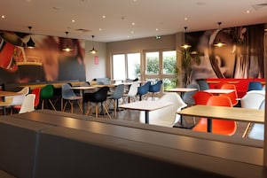 Un restaurante moderno con cabinas y mesas, ventanas amplias y un mural en la pared.