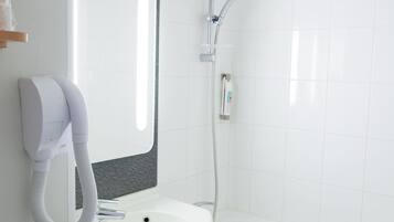 Un baño moderno con un lavamanos blanco, un espejo, un secador de pelo de mano y una ducha.