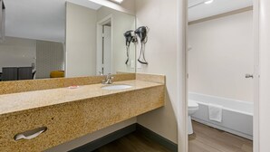 Et badeværelse med vask, spejl, hårtørrer og toilet.