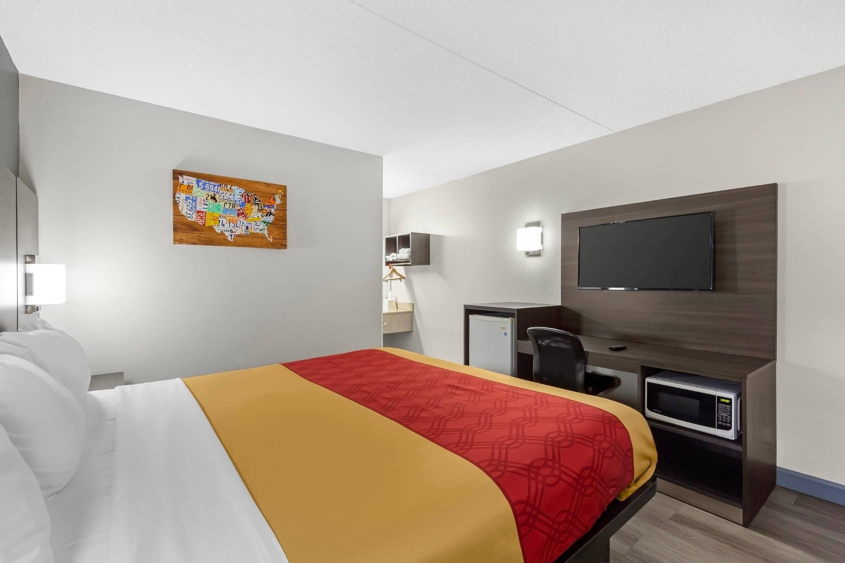 A hotel room with a bed, a desk, a television, and a microwave.