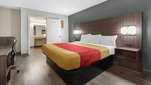 Et hotelværelse med seng, natbord, skrivebord, stol og et spejl.