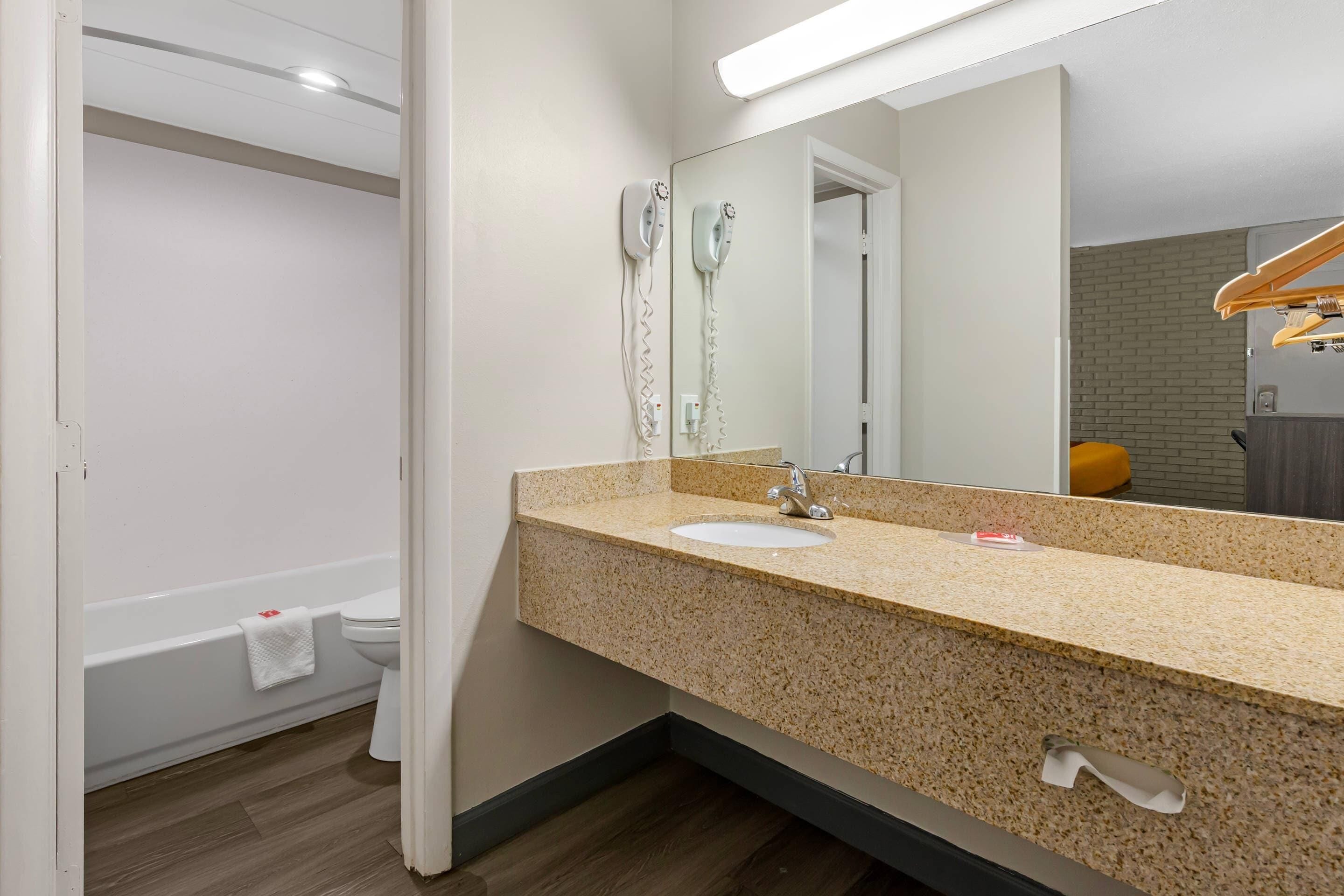 Une salle de bain équipée d’un lavabo, d’un miroir, d’un sèche-cheveux et d’un porte-serviettes.