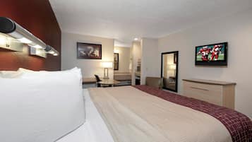 A hotel room with a bed, a desk, a chair, a television, and a mirror.