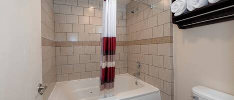 Un baño con bañera, cortina de ducha y toallero con toallas.