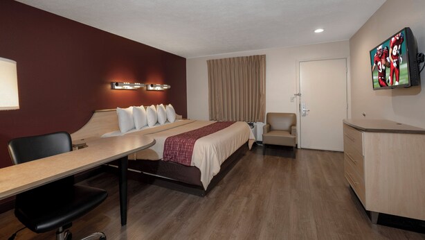 A hotel room with a bed, a desk, a chair, a television, and a wardrobe. - Red Roof Inn Indianapolis - Greenwood (Greenwood)