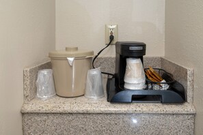 A coffee machine, a trash can, and a glass on a granite countertop. - Red Roof Inn Indianapolis - Greenwood (Greenwood)