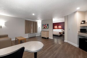 Una habitación de hotel moderna con comedor, cama, televisor y kitchenette.