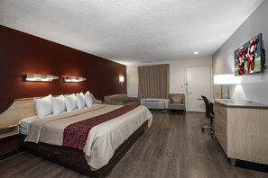 A hotel room with a large bed, a desk, a chair, and a TV mounted on the wall. - Red Roof Inn Indianapolis - Greenwood (Greenwood)