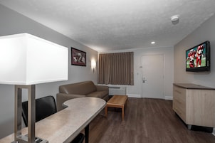 A compact living space with a sofa, a dining table, a TV, and a small kitchenette.