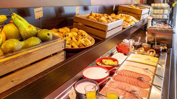 Buffet com diversas opções de comida, incluindo frutas, doces e carnes.