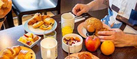 Una mesa de desayuno con cruasanes, fruta, huevos y un muffin.