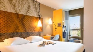 Quarto de hotel com uma cama grande, uma mesa, uma cadeira e uma janela com vista.