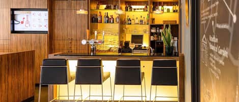 A modern bar area with wooden cabinetry, a bar counter, and four black bar stools.