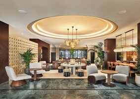 Eine moderne Lobby mit einem runden Tisch in der Mitte, Sitzgelegenheiten und einer dekorativen Decke.