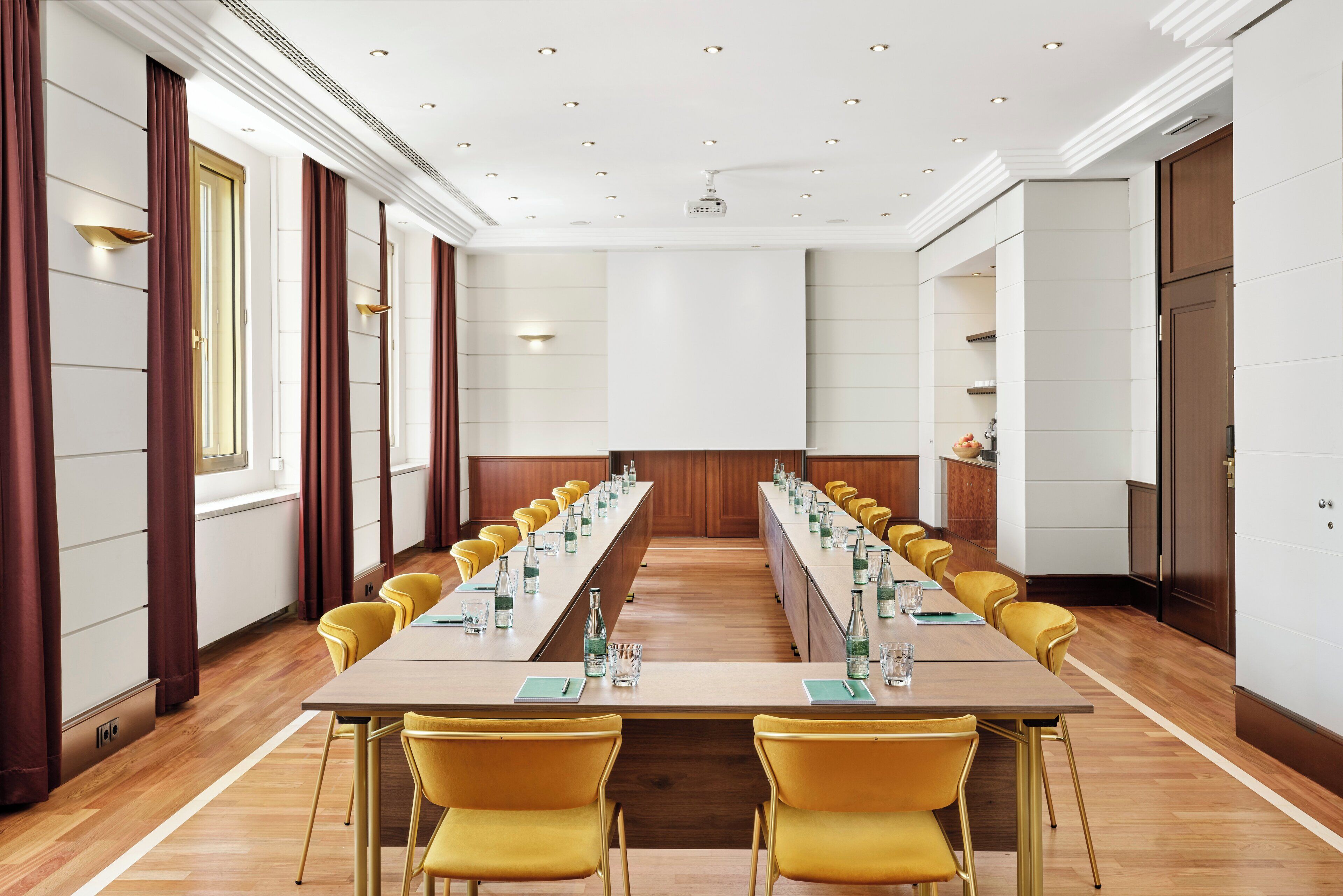 A conference room with a long table, yellow chairs, and a projector.