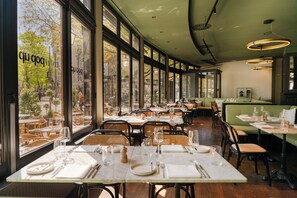 Ein Restaurant mit gedeckten Tischen, großen Fenstern und Blick auf die Straße.