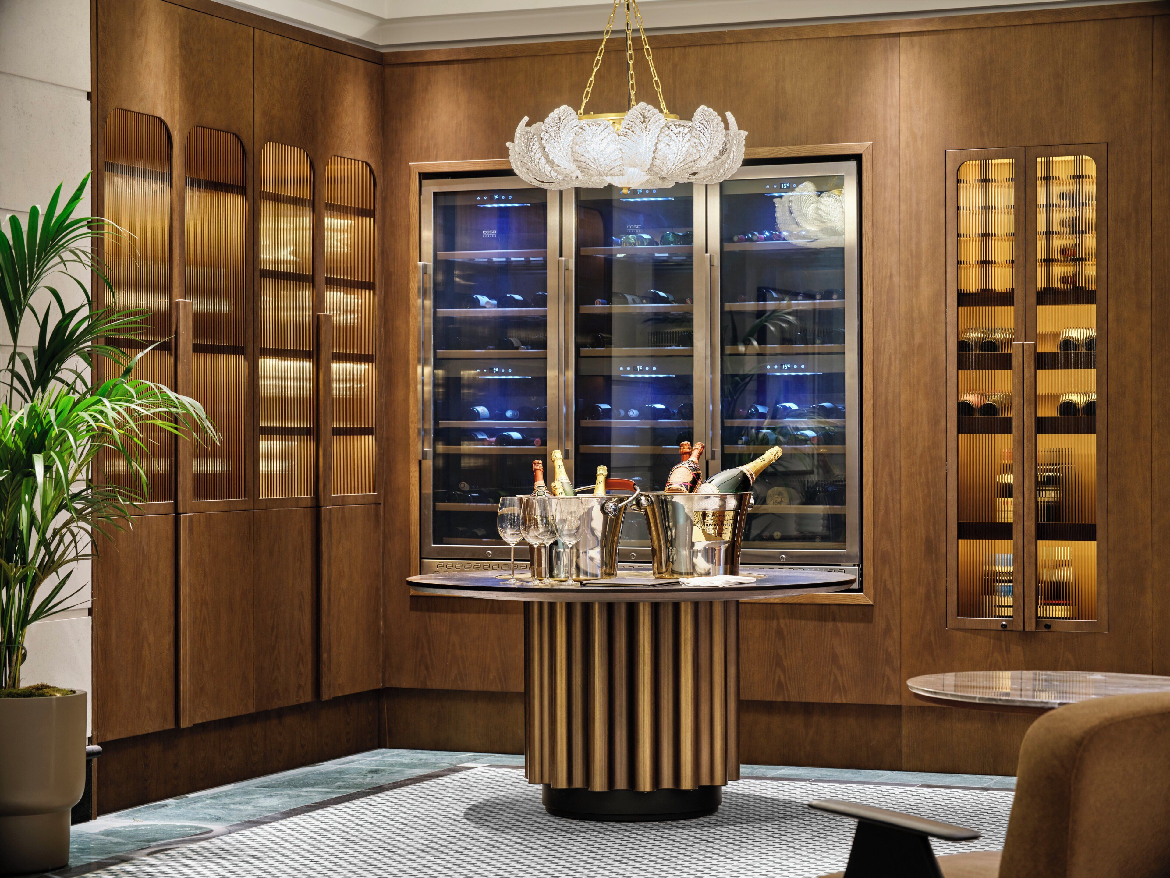 A modern interior with a wooden panel wall, a wine display, and a chandelier.