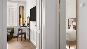 A hotel room with a bed, a desk with a chair, a large mirror, and a window with curtains. - Bristol Berlin Vignette Collection by IHG (Berlin)