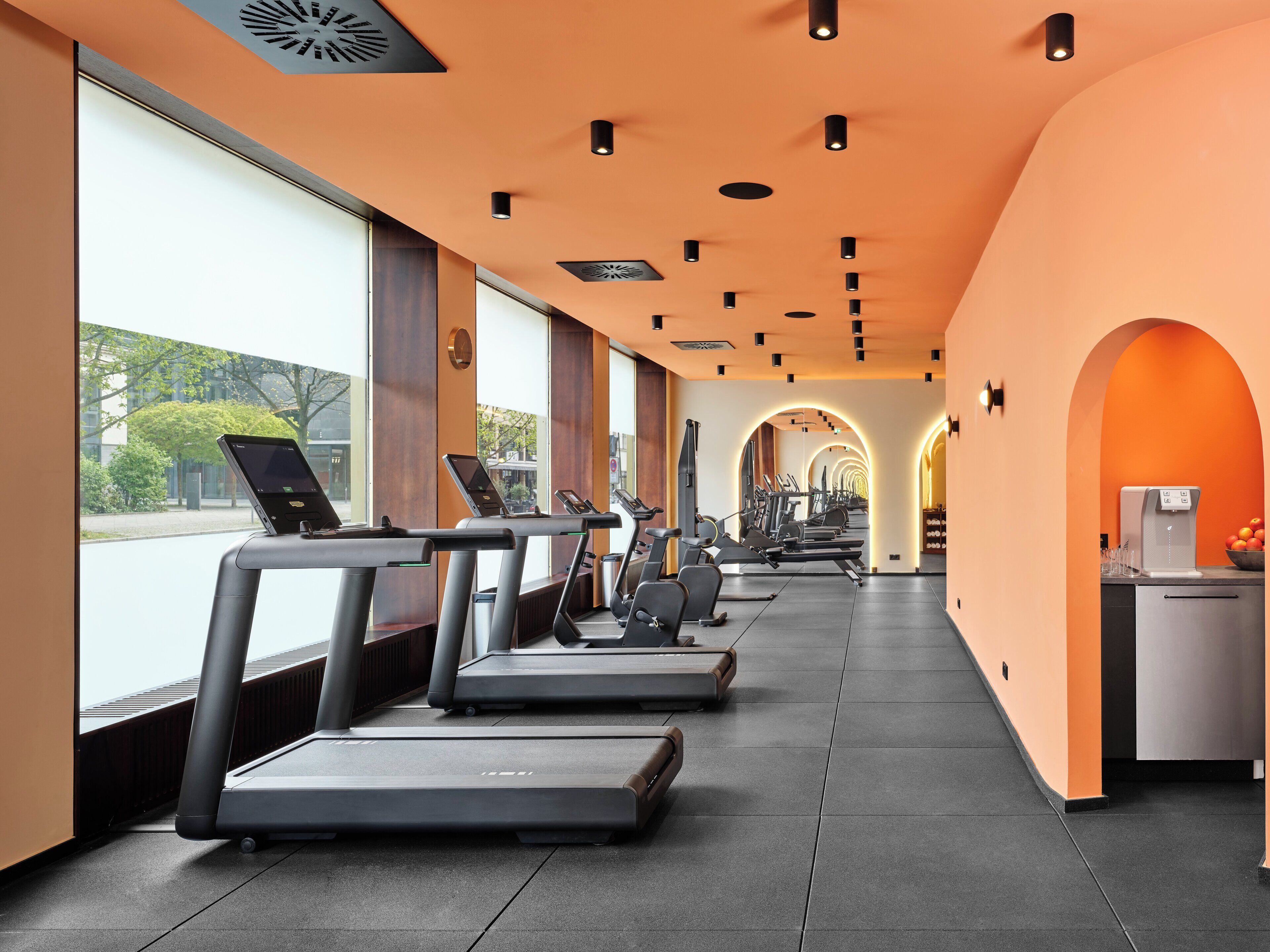Un gimnasio con cintas de correr, equipo de ejercicio y una máquina de café.