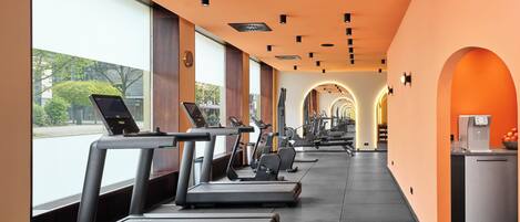 Un gimnasio con cintas de correr, equipo de ejercicio y una máquina de café.