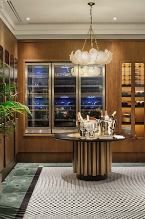 A dining area with a chandelier, wine racks, and a view through a large window. - Hotel Bristol Berlin (Berlin)