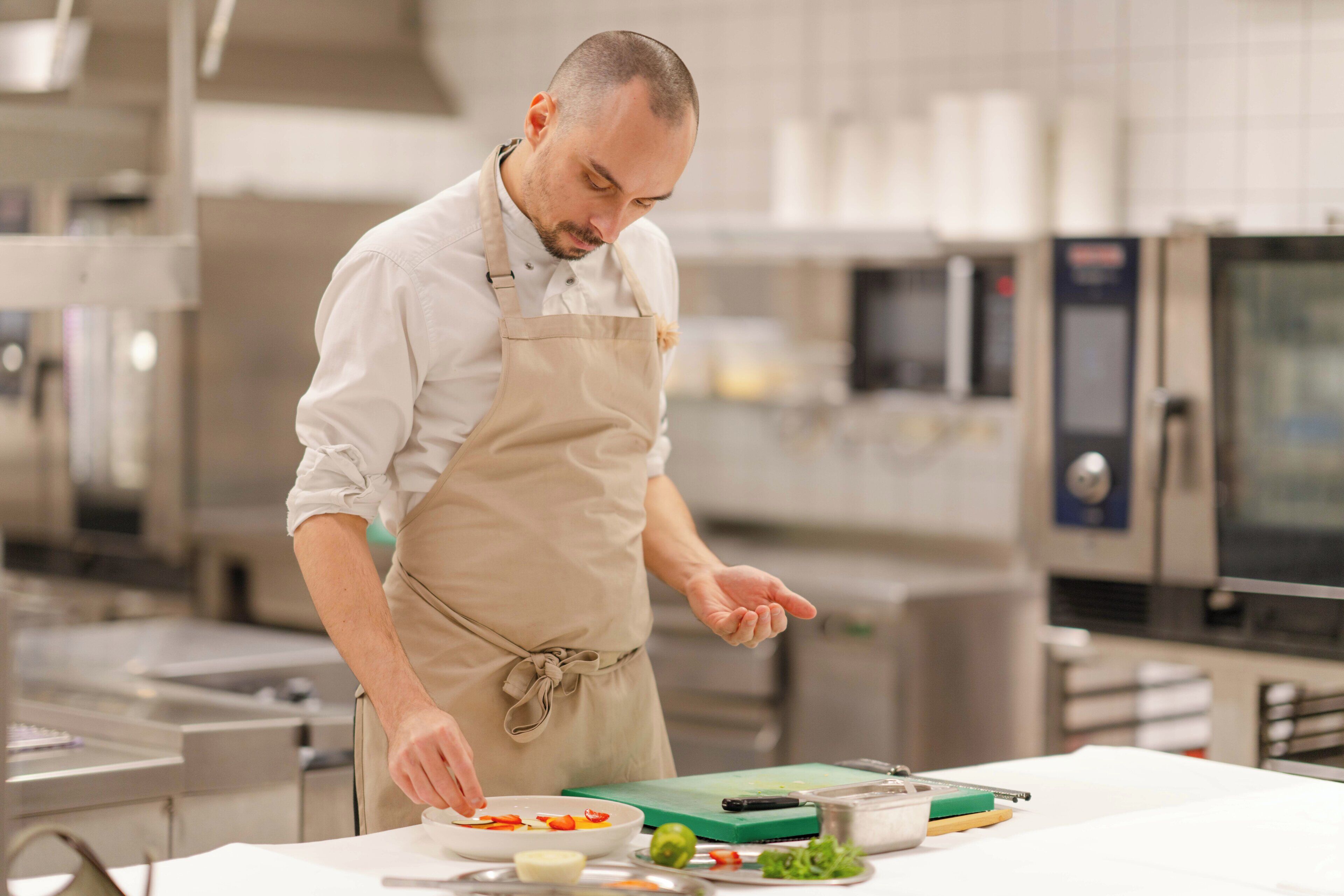 A chef in a professional kitchen with stainless steel appliances and a clean, organized workspace.
