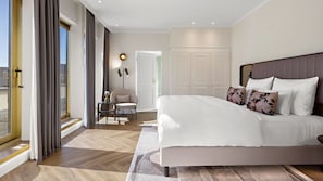 Un dormitorio moderno con una cama grande, una silla, un escritorio y vistas al exterior.