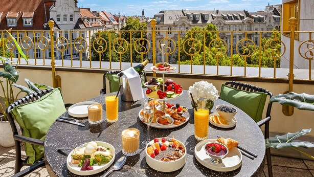 A round table with a variety of breakfast items including fruits, pastries, and beverages, set against a backdrop of a cityscape. - Bristol Berlin Vignette Collection by IHG (Berlin)