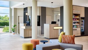 A modern lobby with a reception desk, seating area, and a visible store named 'the market'. - Courtyard by Marriott Magdeburg (Barleben)