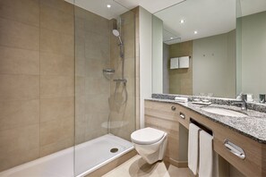 A modern bathroom with a glass-enclosed shower, a white toilet, and a granite countertop with a sink. - Courtyard by Marriott Magdeburg (Barleben)