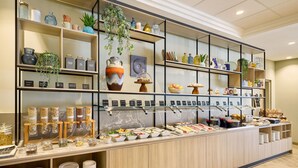 A buffet area with various food items, jars of condiments, and decorative plants. - Courtyard by Marriott Magdeburg (Barleben)