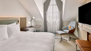 A hotel room with a large bed, a desk with a lamp, a TV, and a chair. - Courtyard by Marriott Magdeburg (Barleben)